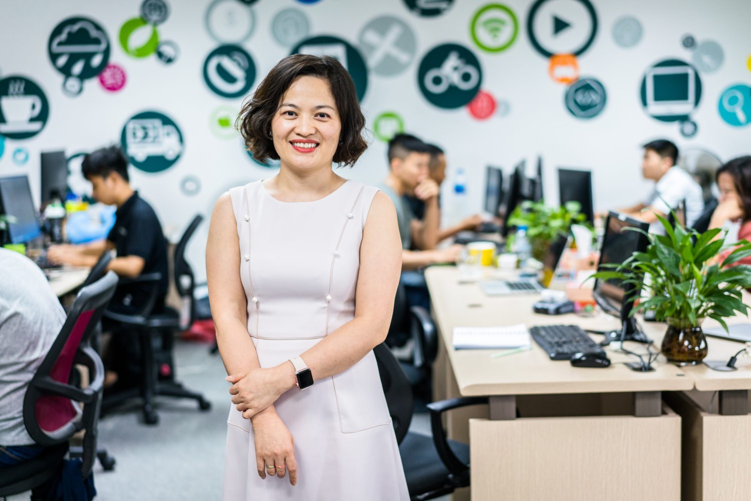 Van Dang CEO at Savvycom and former mentee and mentor poses in her office as employees work behind her