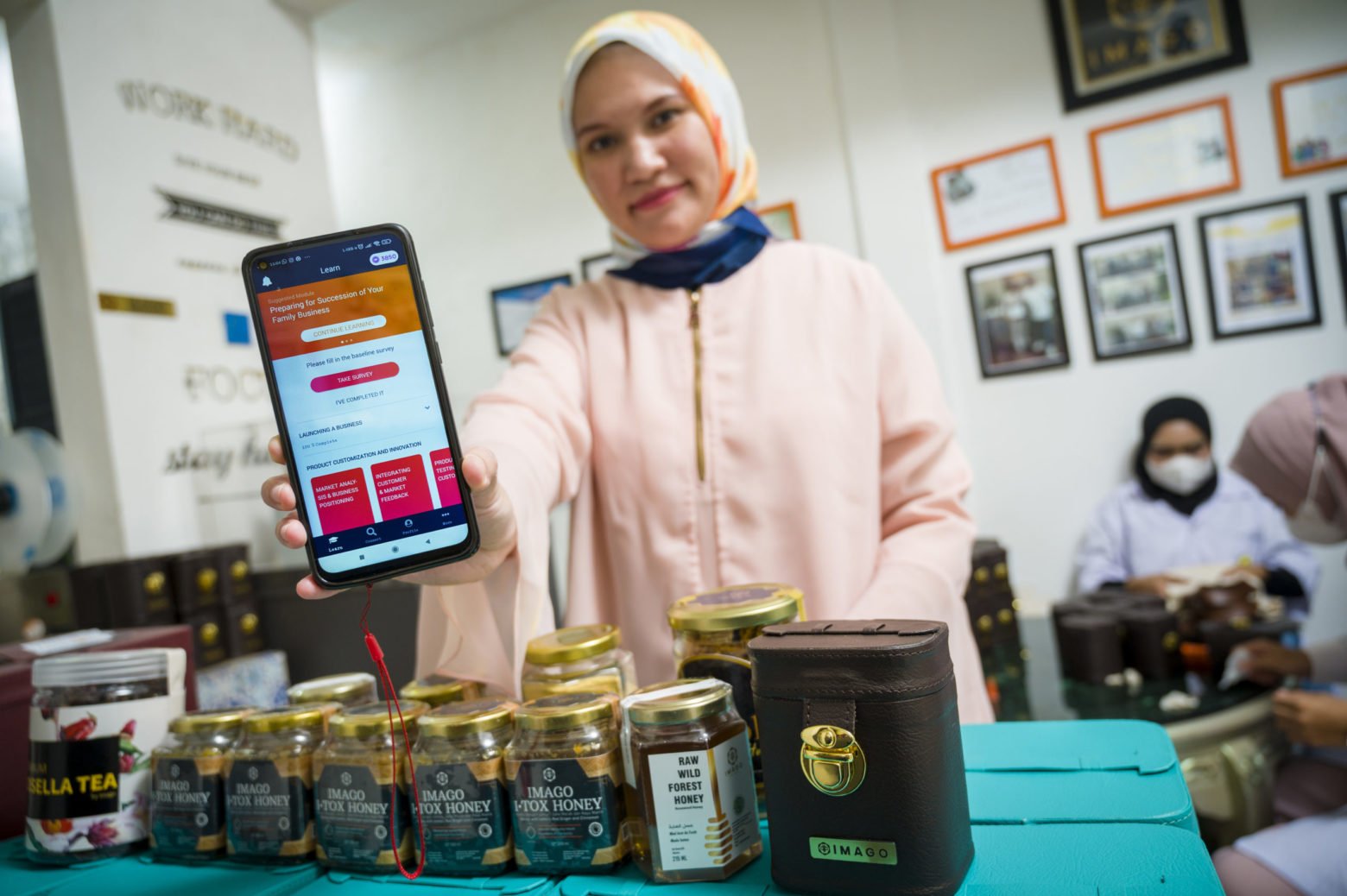 Shinta Aviyani, founder of Imago Raw Honey, and WEAVE alumna, holds up the HerVenture app