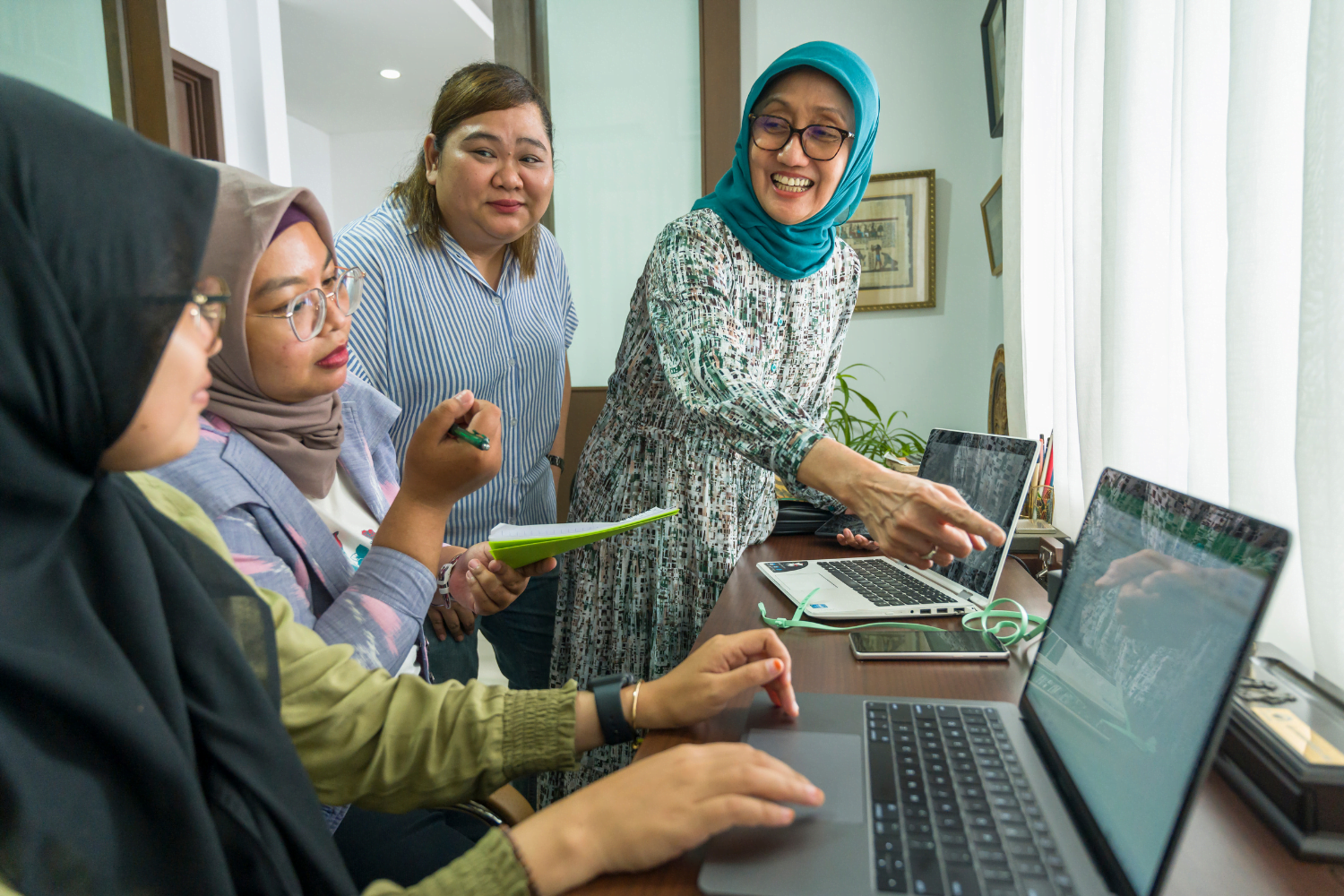 Jullie Hakim, founder of Bhumi Rasa, and WEAVE alumna works on a computer with her staff