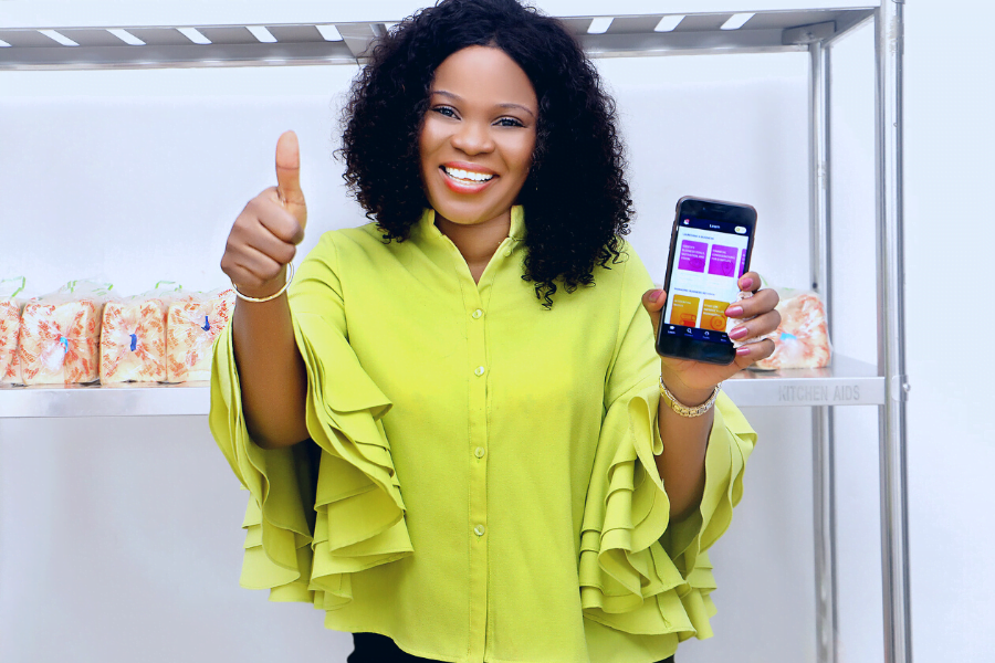 A woman entrepreneur gives a thumbs up while holding up the HerVenture app