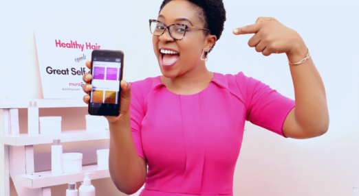 A woman entrepreneur points to the HerVenture app on her phone while smiling
