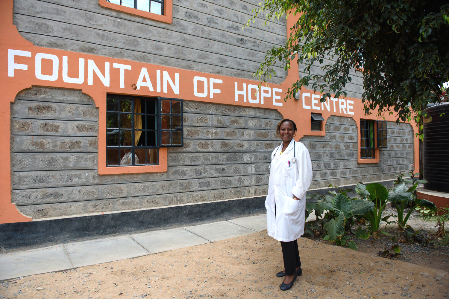 Dr. Catherine Amulundu poses with the Fountain of Hope Centre sign