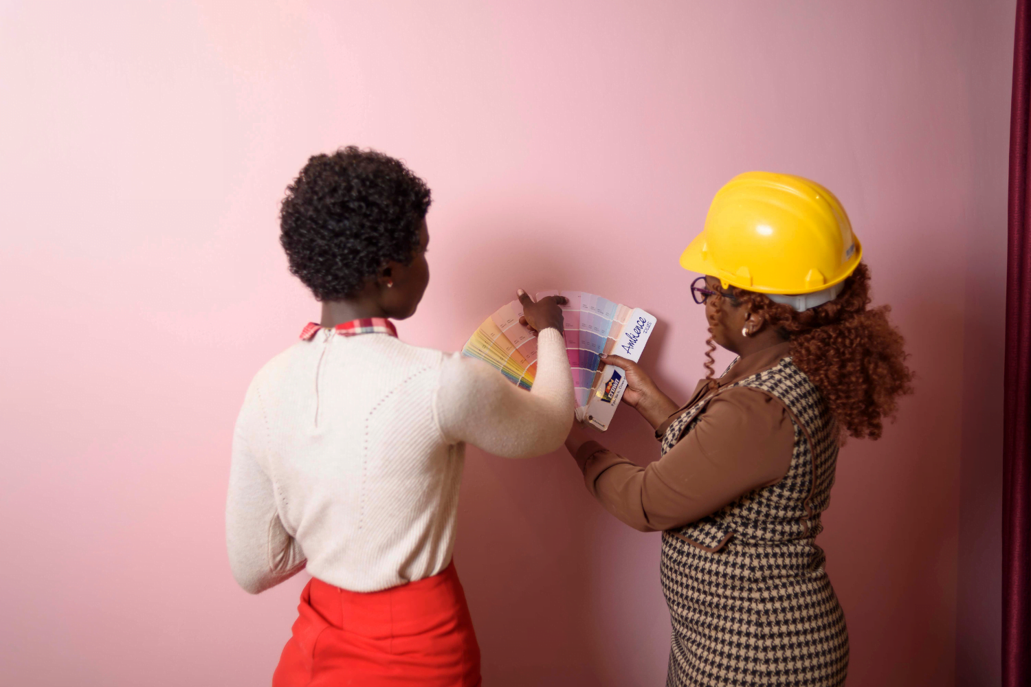 Gill Ingosi shows a client some color samples while in front of a pink wall