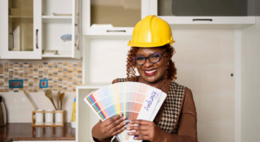 Gill Ingosi holds up paint samples and smiles in a kitchen