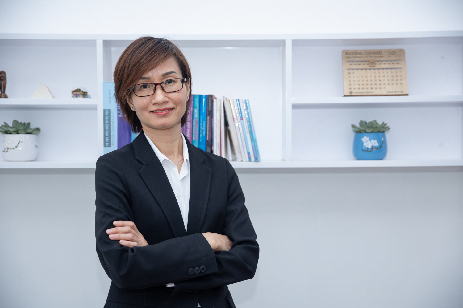 Mai Thi Le Quyen poses in front of a book shelf at her law firm in Vietnam