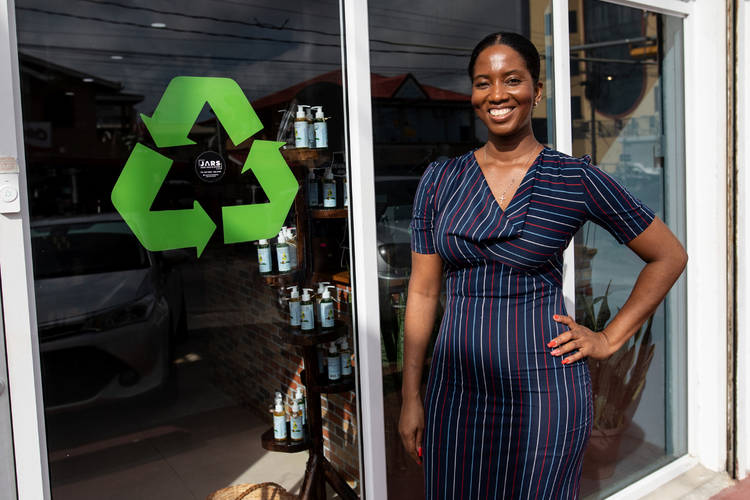 Alana Bunbury-Walton poses with the recycling sign at JARS zero waste store in Guyana