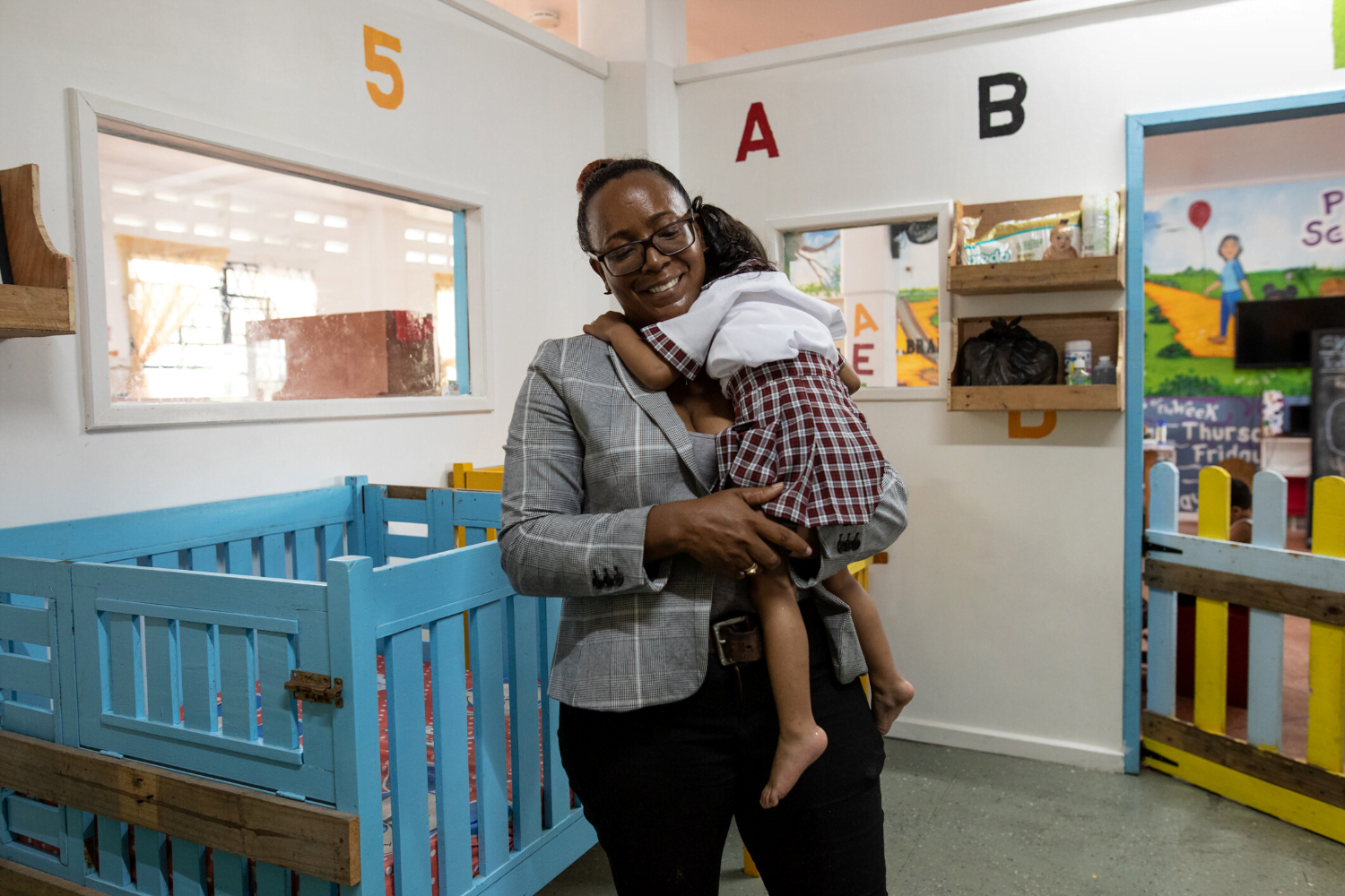 Carlotta John holds child at daycare centre in Guyana