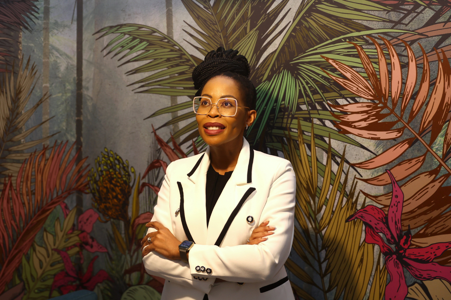 Queen Mokulubete, Founder of Somila Engineering, poses in front of a palm tree wall painting in her office.