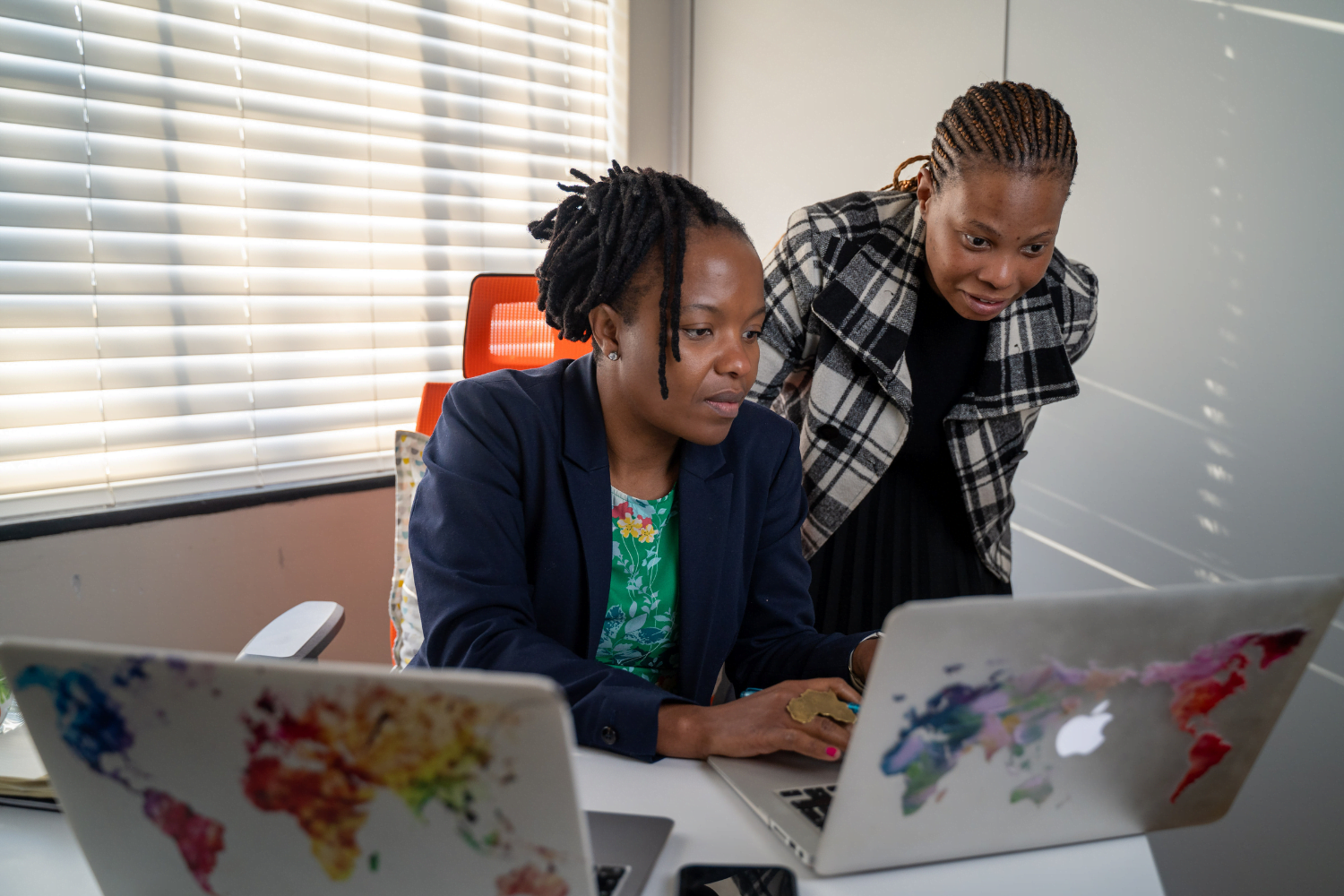 Dudu Makhari, Founder of Ngangezwe Foundation in South Africa, is sat in her office on the laptop, showing a male employee something on the computer.