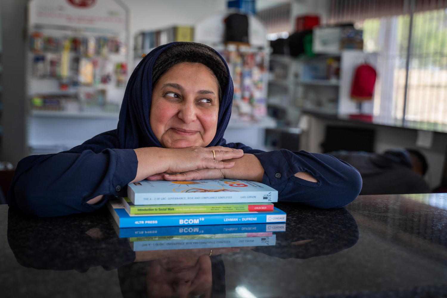 Shereen Cassim Hassim, a female entrepreneur, rests her head on some books.