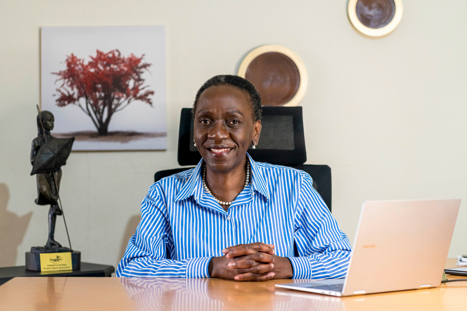 Frida Owinga, Owner of Passion Profit in Nairobi Kenya smiles at her desk.