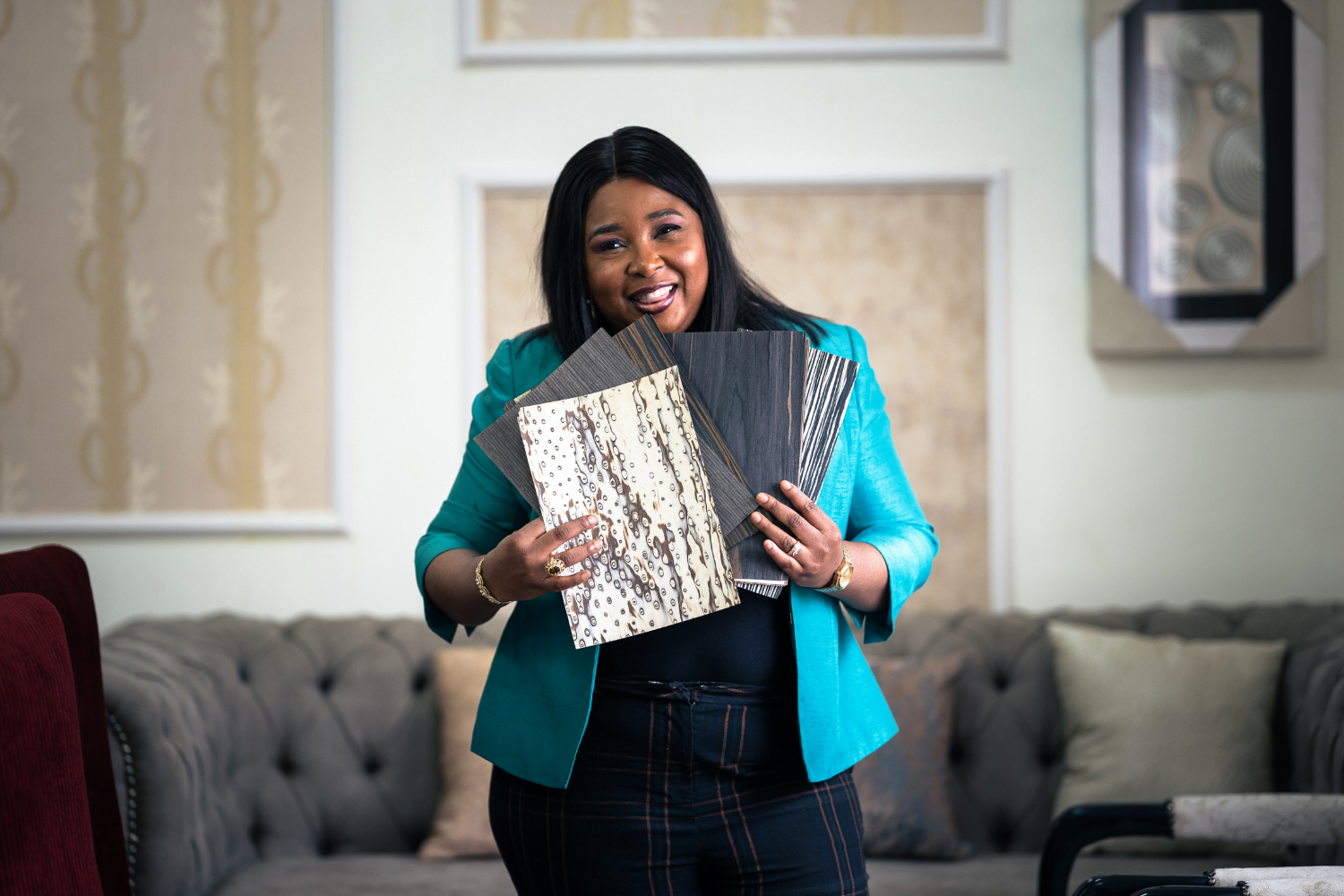 Glory Omoregie, CEO of Home Craft Interiors and Projects in Lagos, Nigeria holds up wood flooring samples.