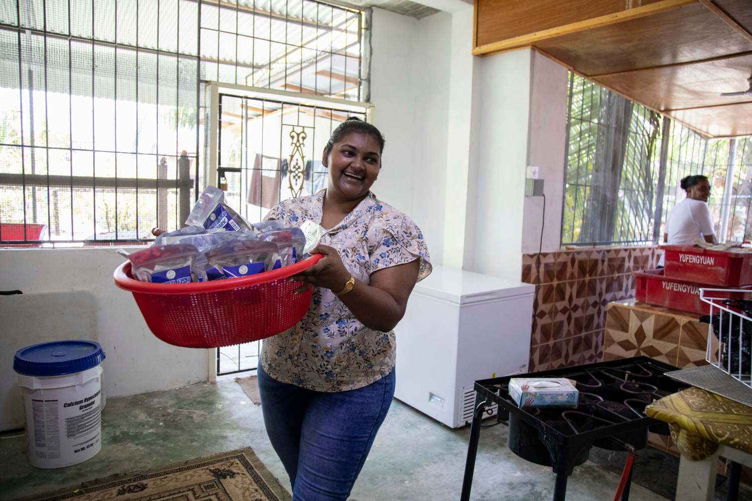 Radhika Basdeo, Sole Proprietress of Basdeo's Dynasty in Georgetown, Guyana, carries a large bin of her products.