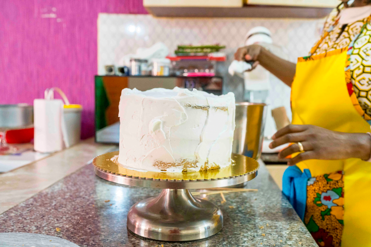 Esther Gathage, Owner of Herstees Bespoke Cakes, frosts a vanilla cake.