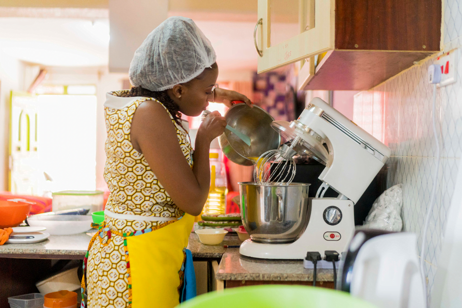 Esther Gathage, Owner of Herstees Bespoke Cakes, adds ingredients to her mixer.