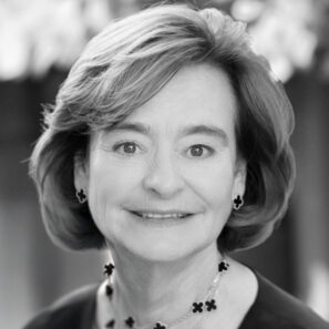 Cherie Blair smiles at the camera. She is a white woman with brown hair in a short bob, wearing a black plain top and a necklace.